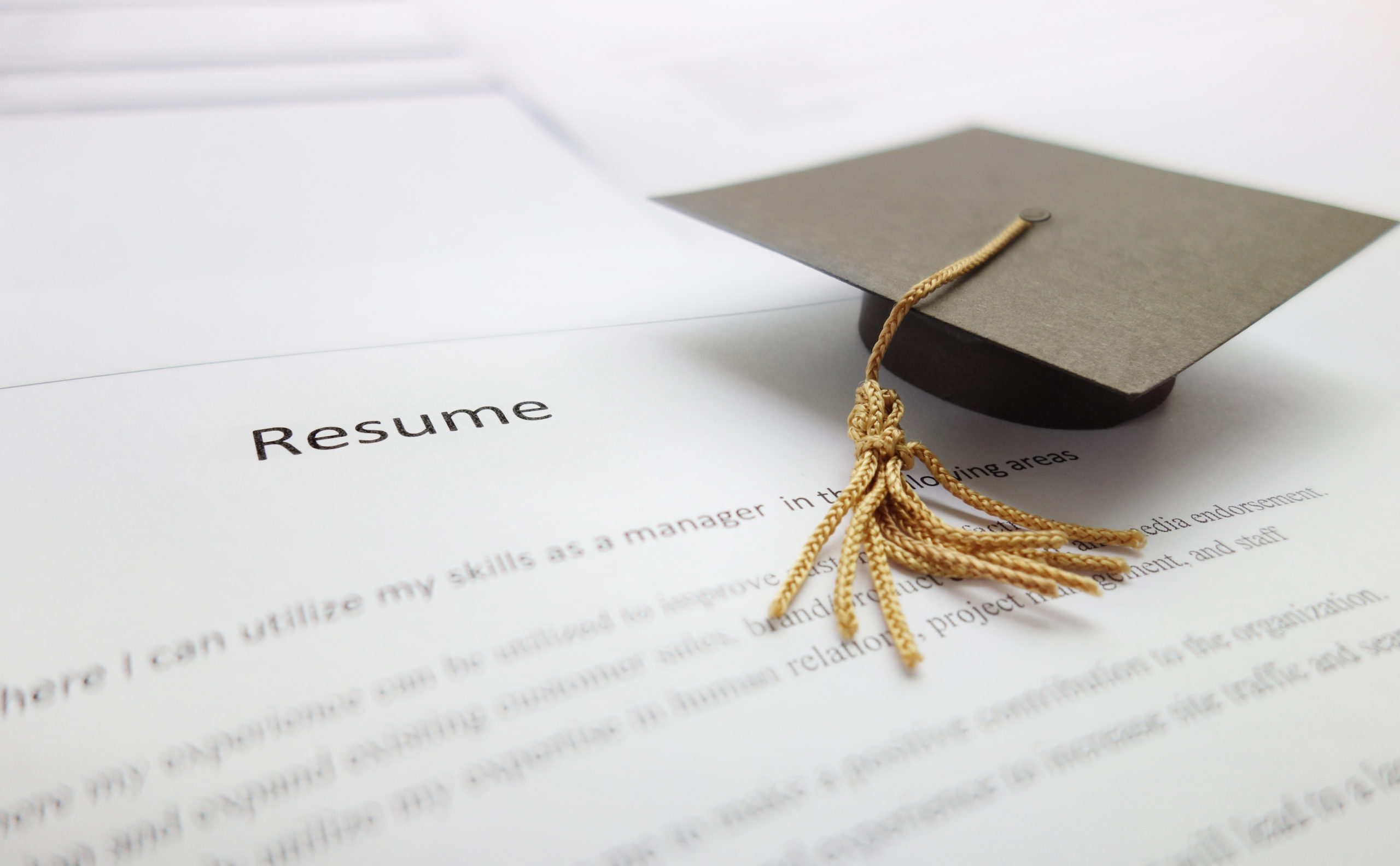 Job resume Small graduation cap on a resume - recent college graduate concept