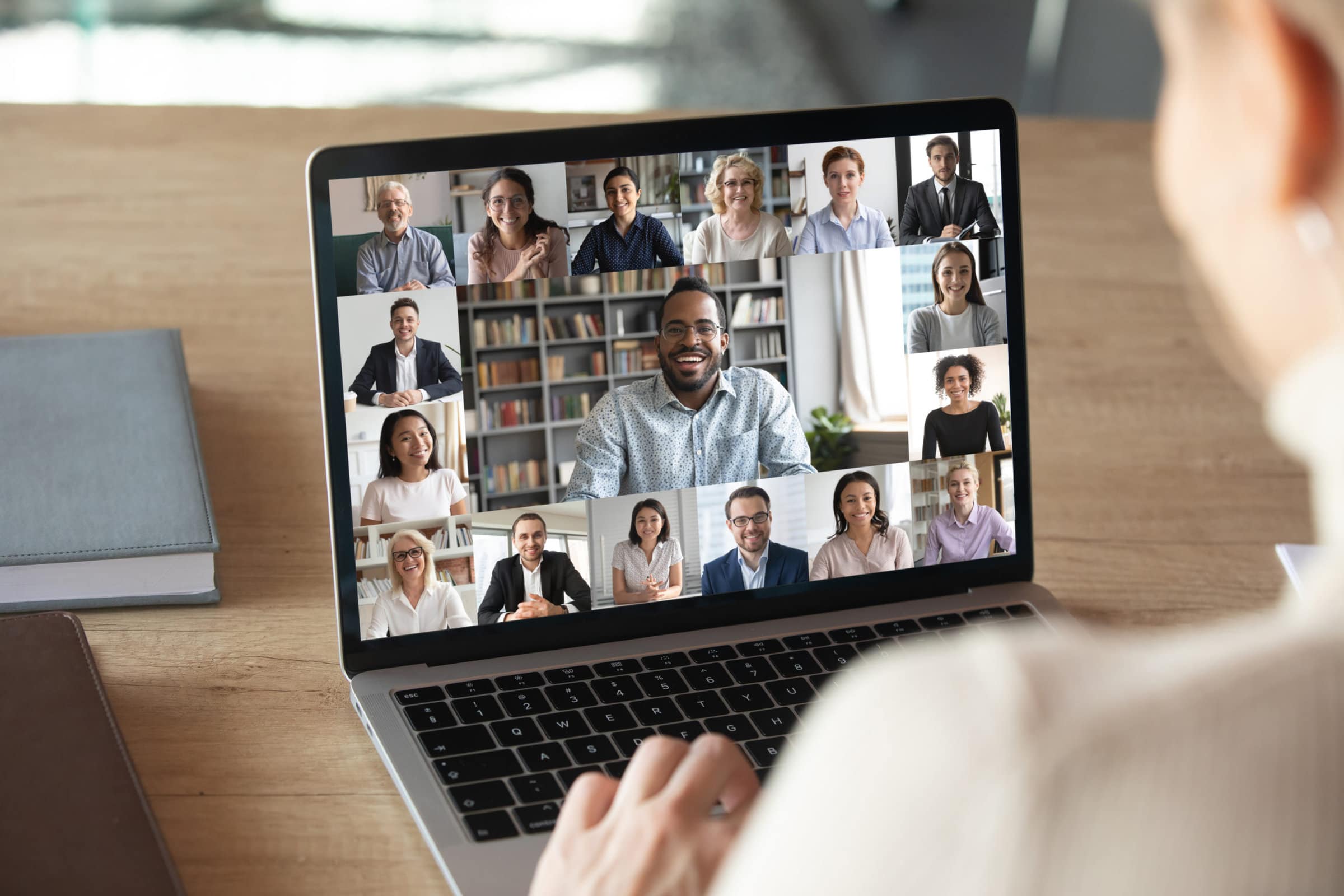 Back view of female employee speak talk on video call with diverse multiracial colleagues on online briefing, woman worker have Webcam group conference with coworkers on modern laptop at home