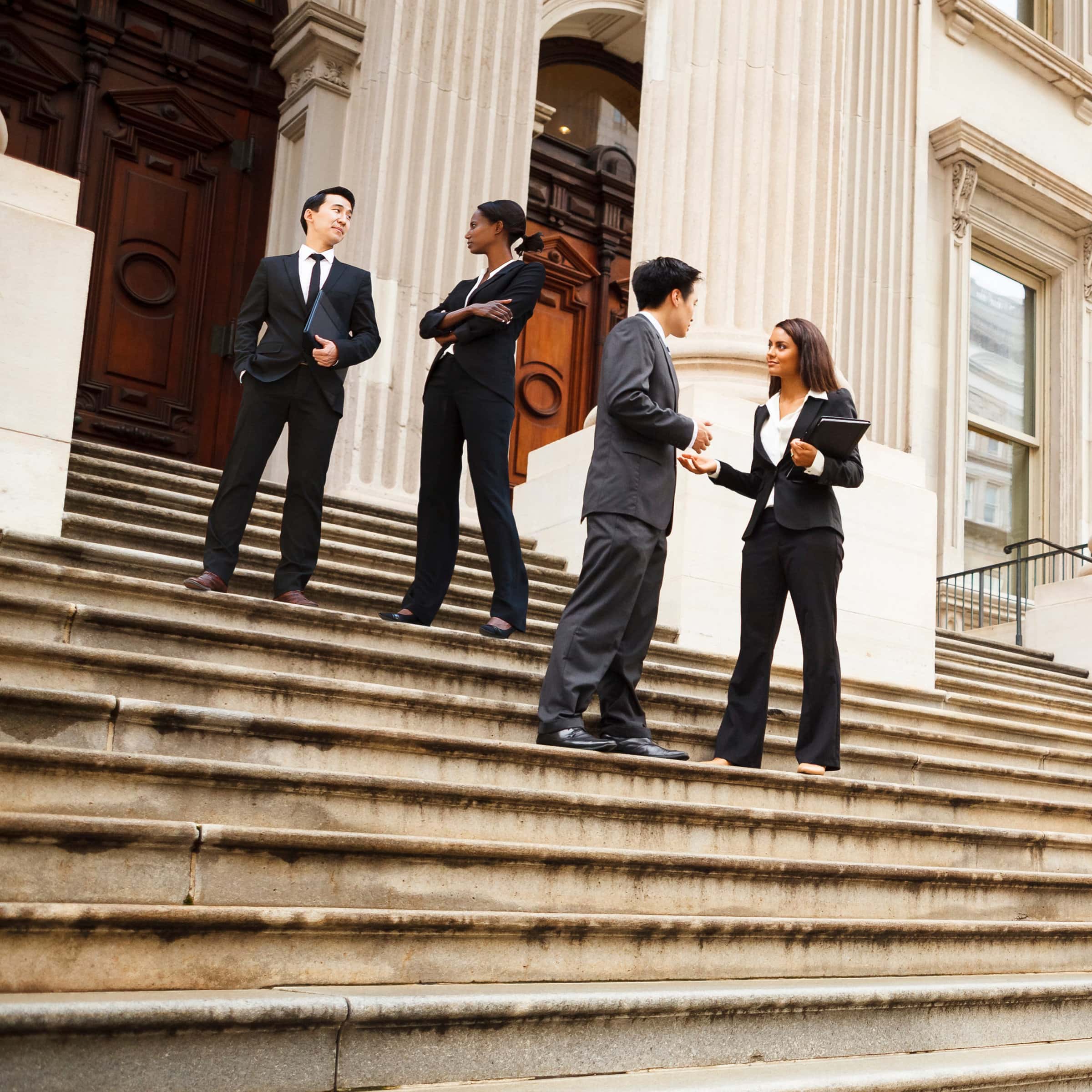 Professionals in Discussion on Staircase Four well dressed professionals in discussion on the exterior steps of a building. Could be lawyers, government workers, business people etc.