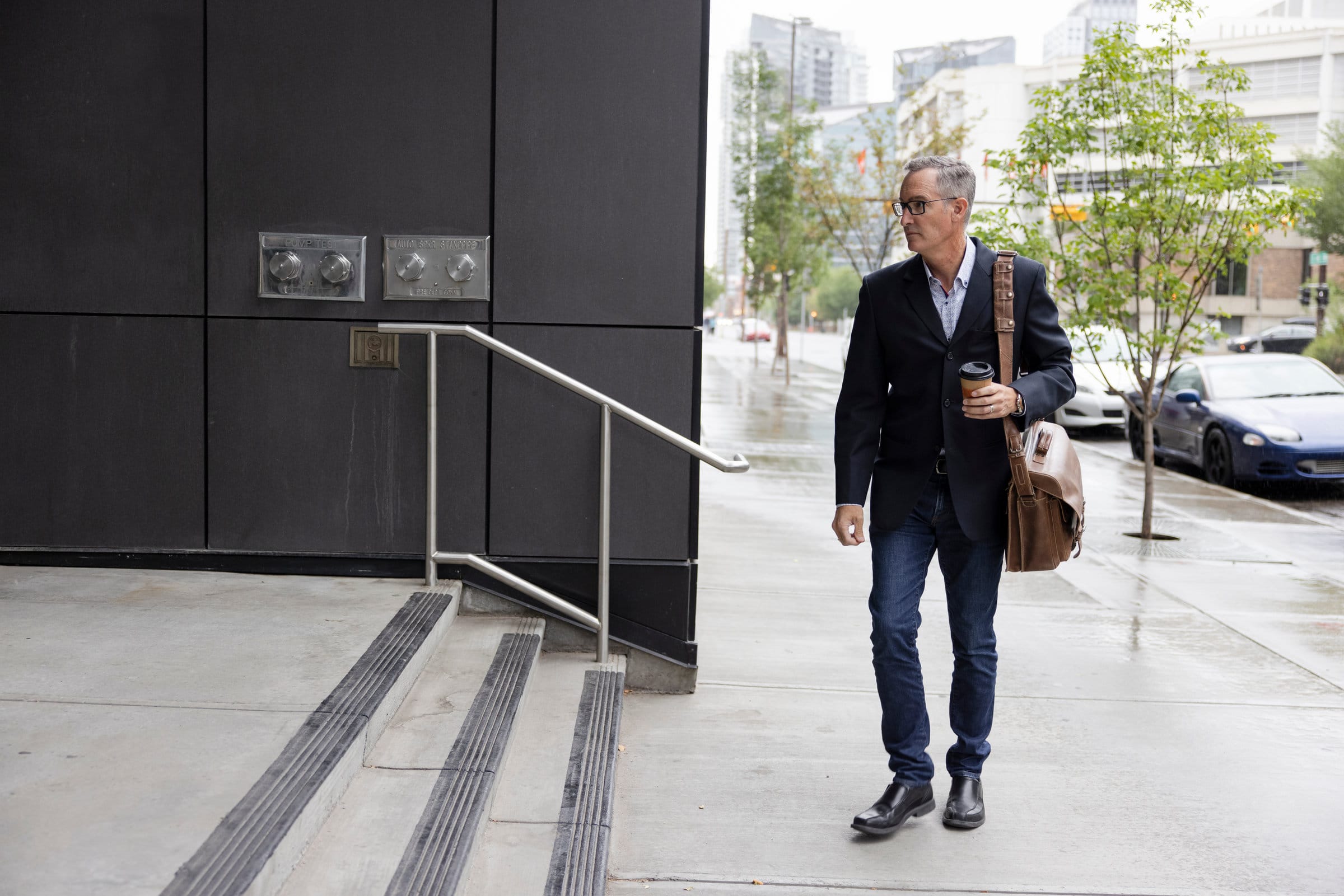 Businessman with hot drink standing in front of office building