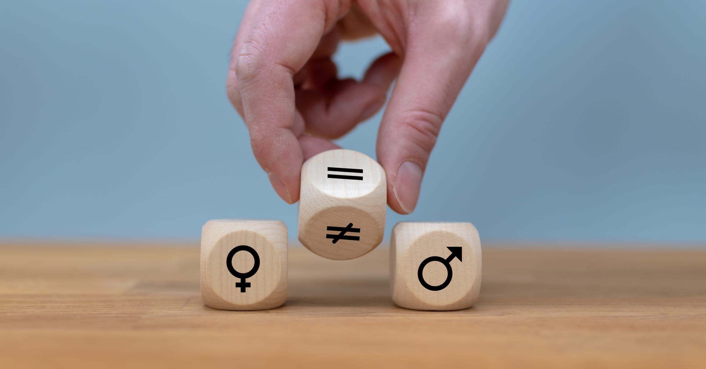 Symbol for gender equality. Hand turns a dice and changes a unequal sign to a equal sign between symbols of men and women. Symbol for gender equality. Hand turns a dice and changes a unequal sign to a equal sign between symbols of men and women.