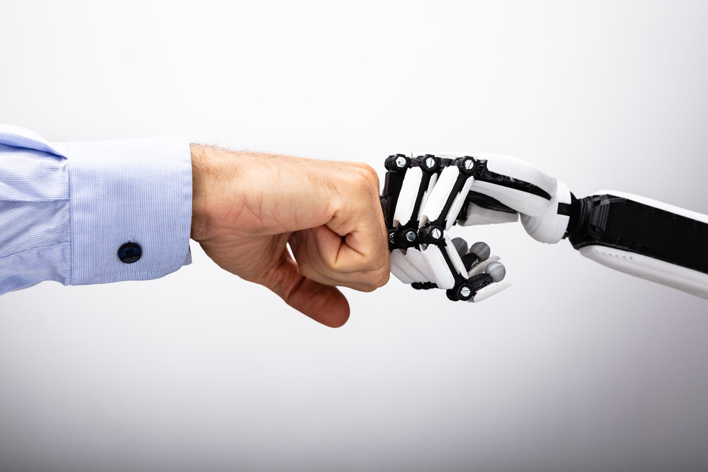 Human Hand And Robot Making Fist Bump Human Hand And Robot Making Fist Bump On Gray Background