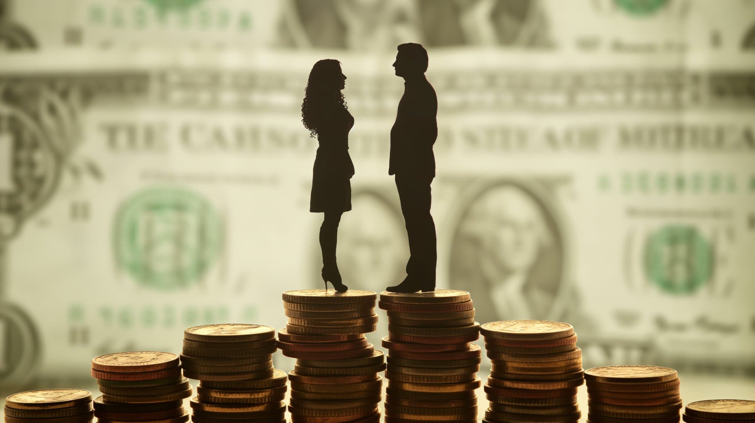 Silhouettes of a man and a woman standing on stacks of coins on a blurred background of money. Concept of gender equality in pay.Pay equity concept