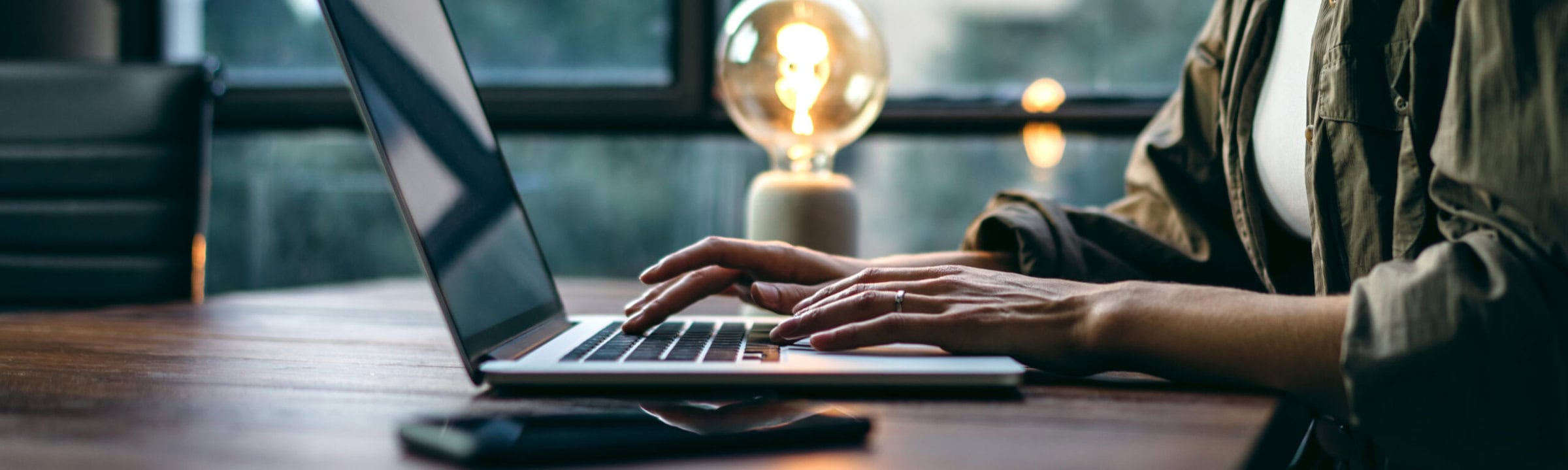 Young woman working with a laptop. Female freelancer connecting to internet via computer. Blogger or journalist writing new article. Close-up of female hands typing on keyboard