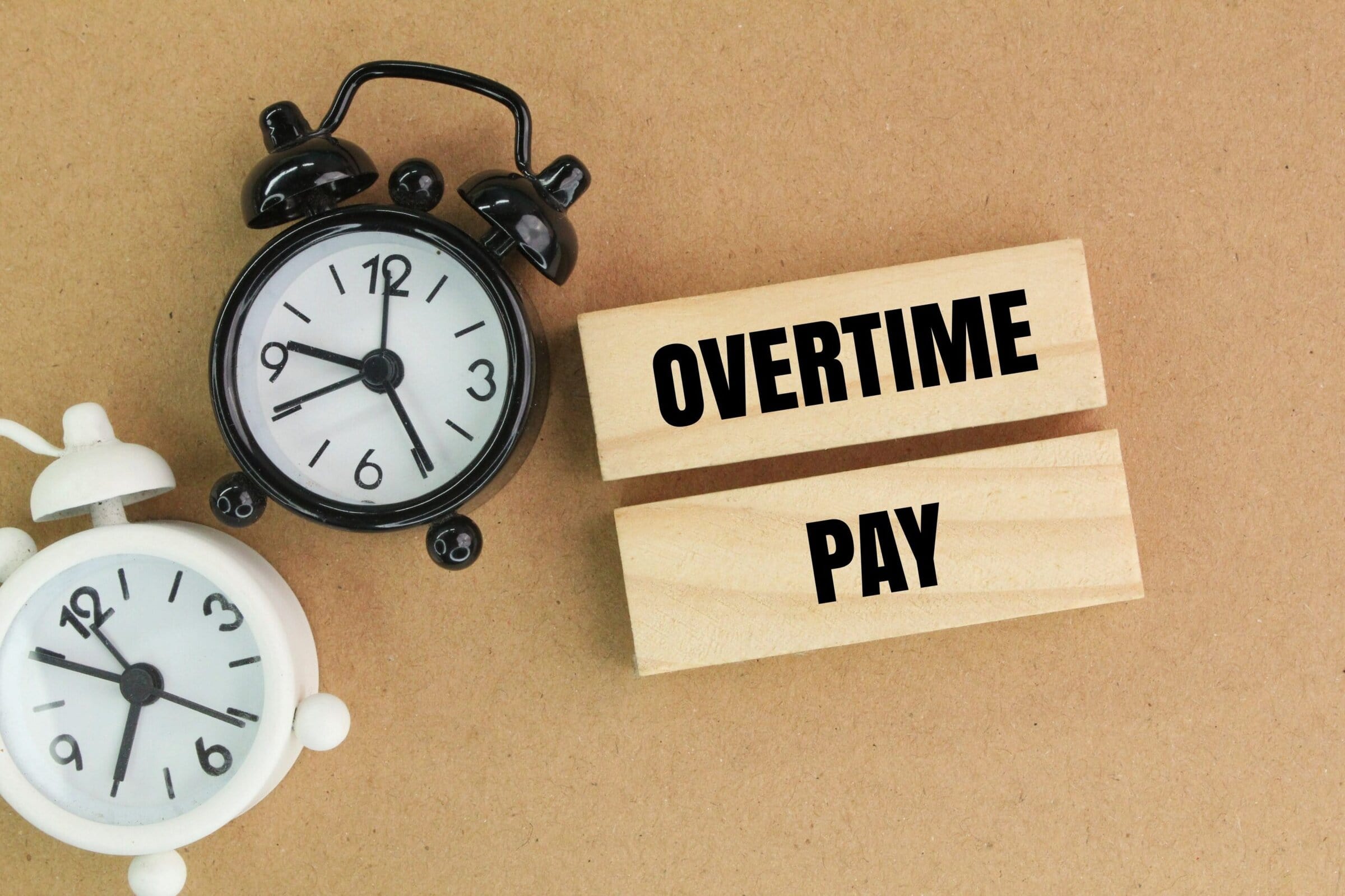 two clock bells and a stick with the words Overtime pay. the concept of overtime or payment by time