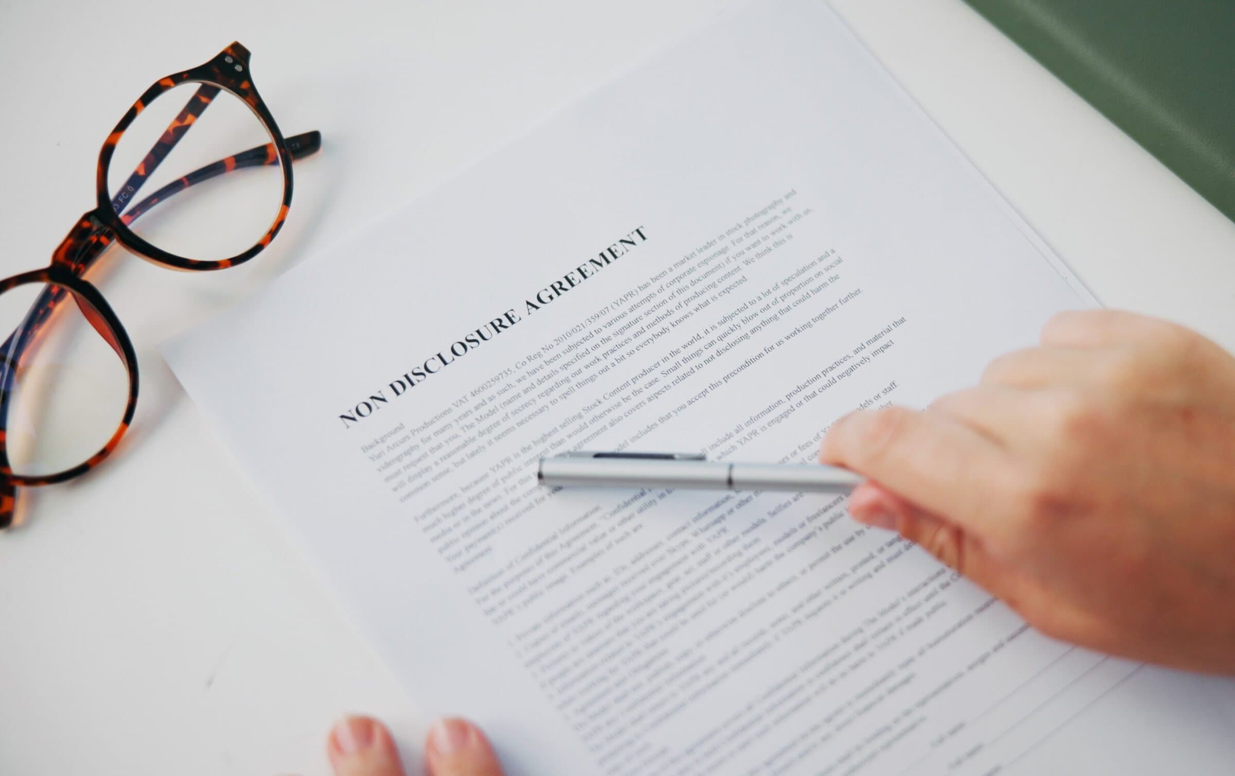 NDA Hands, document and non disclosure agreement at office with reading, review and legal compliance. Person, attorney and paperwork for privacy, secret and check information with contract from above